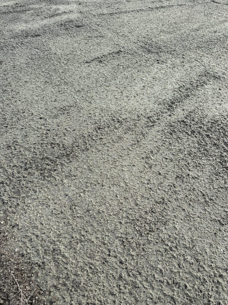 Unpaved haul road surface sealed with a sprayed dust-binding layer