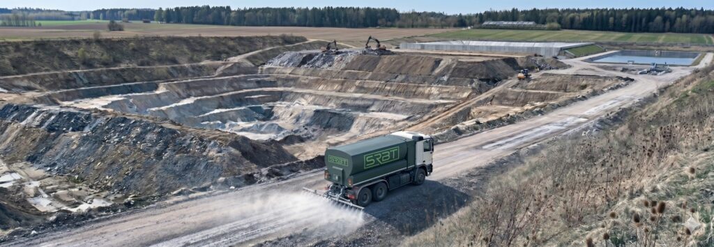 SRBT tanker spraying dust suppressant along a quarry haul road