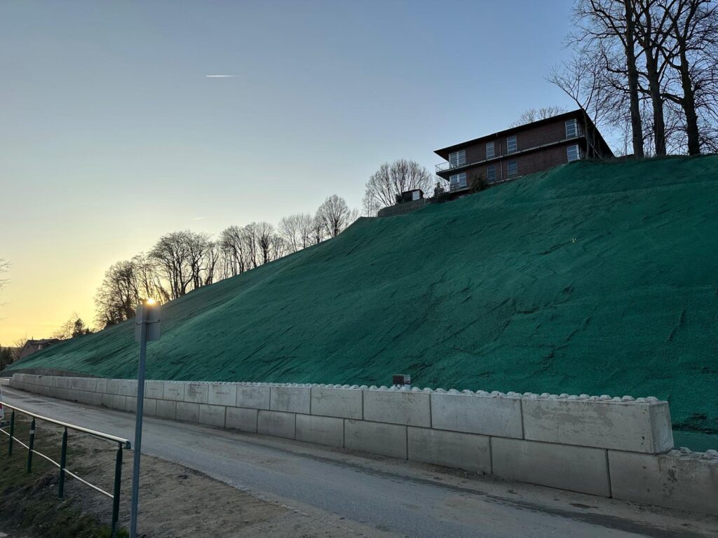 Erosion control mulch on an embankment above a retaining wall Freshly hydroseeded embankment with green erosion control mulch above a retaining wall