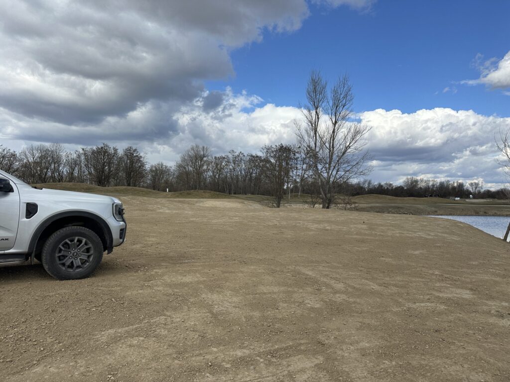 Graded bare soil area beside a retention pond before revegetation