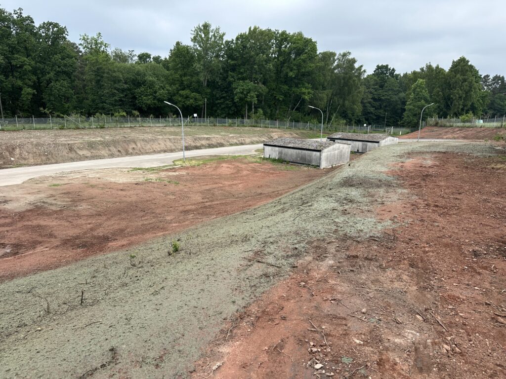 Freshly hydroseeded slope with green mulch beside an industrial site