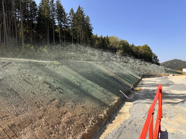 Hydroseeding a freshly cut slope on a road construction site