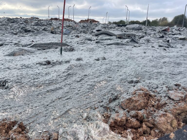 Sprayed dust-binding layer covering an active landfill surface