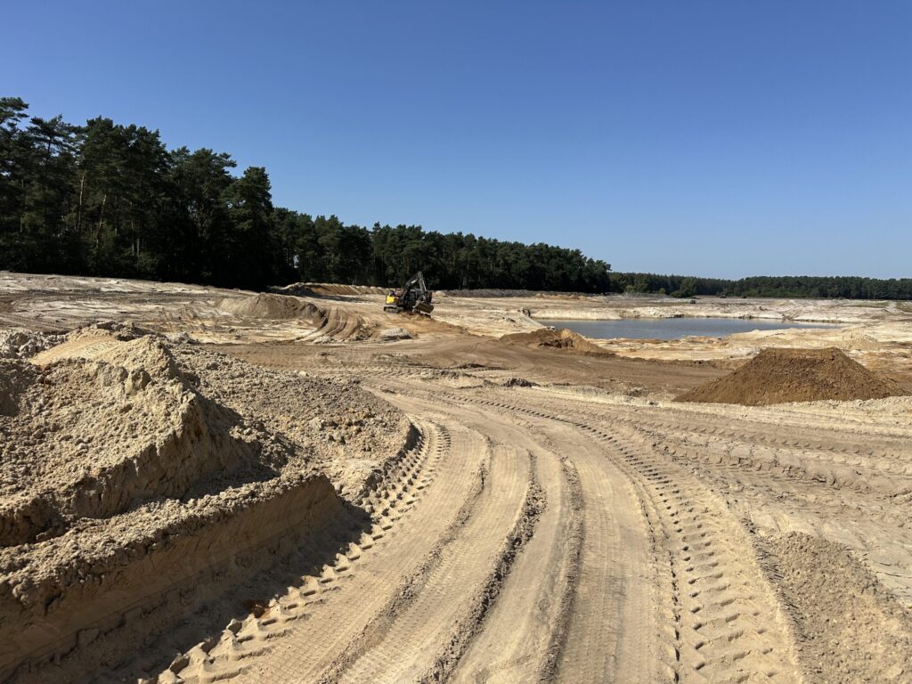 Open sand quarry with haul routes and an excavator at work